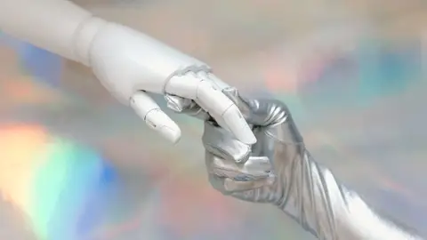 Close-up of a robot hand and silver-gloved hand touching, symbolizing human-robot connection.