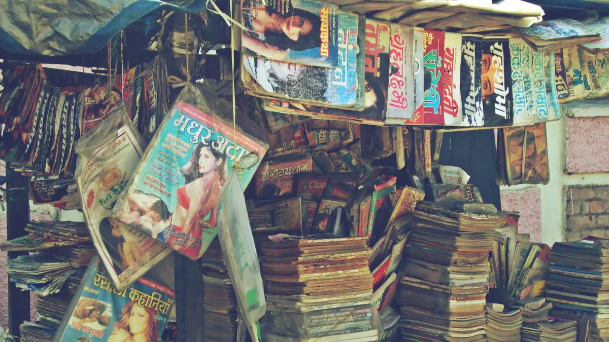 A retro outdoor kiosk featuring stacks of vintage magazines and publications.